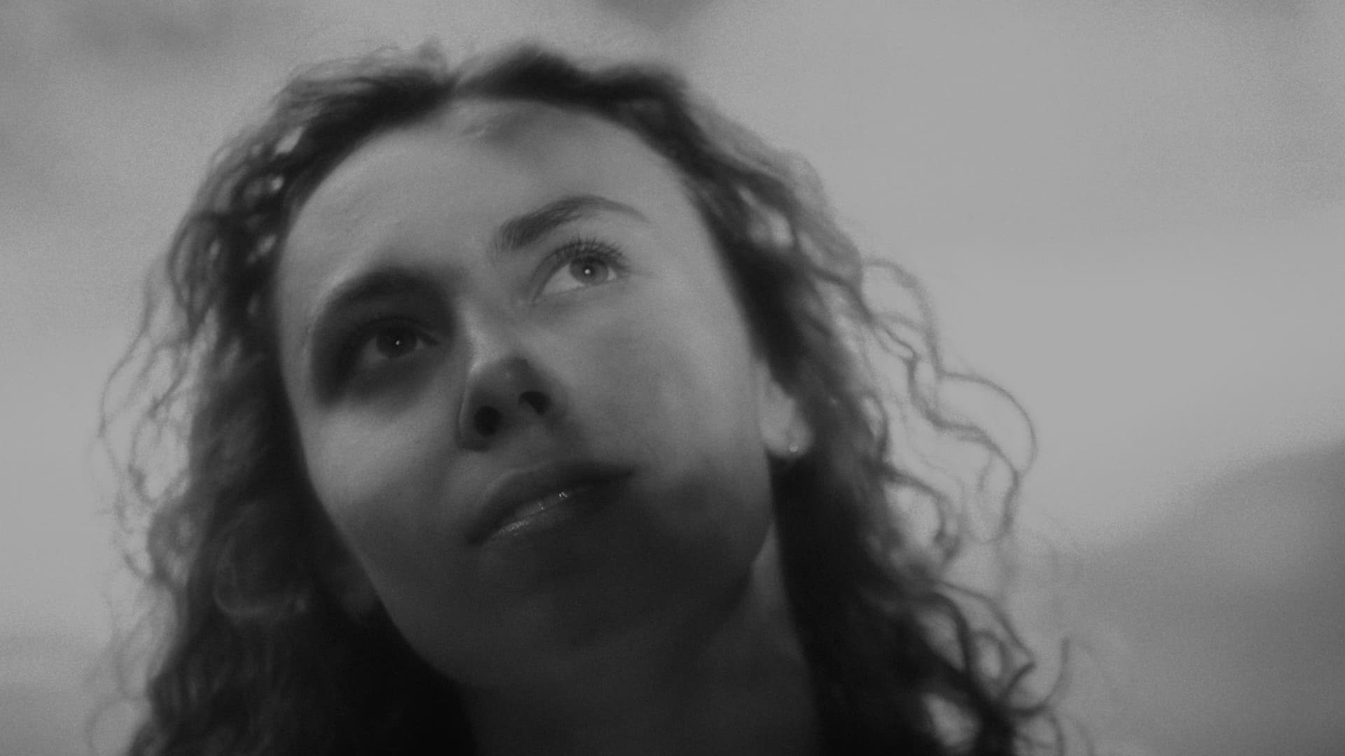 Vrouw kijkt omhoog naar de lucht, zwart-wit
